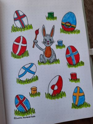 Painting of an Easter bunny holding a paint brush and sitting among Easter eggs painted like the Nordic flags